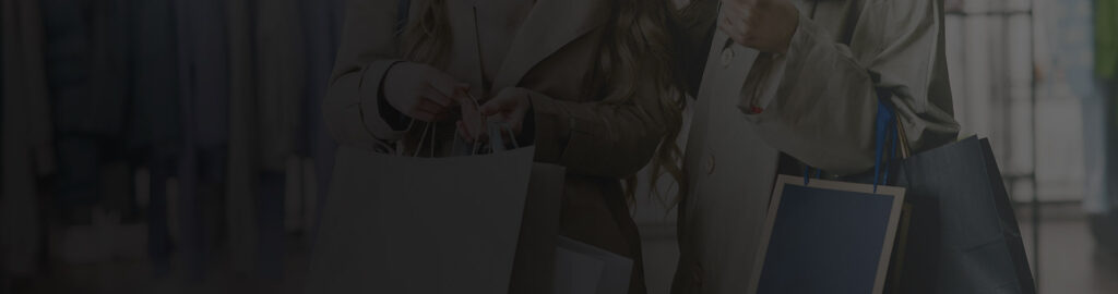 Deux personnes portant à leurs bras plusieurs sacs de shopping